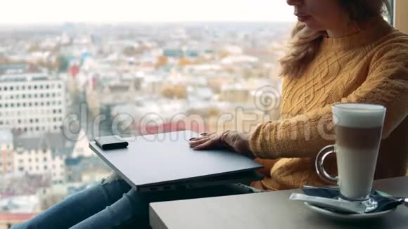 一位商务女性使用笔记本电脑坐在城市视野的对立面视频的预览图