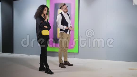 无聊的男人和女人站在画廊的抽象画面前视频的预览图