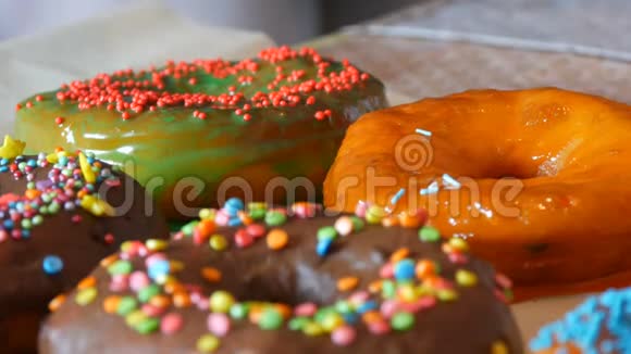 一张桌子上连续摆着许多五颜六色的新鲜油炸甜甜圈一个美丽的甜圈和橙色的糖衣洒在视频的预览图