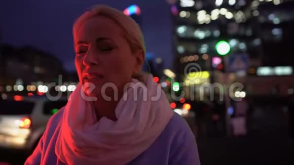 50岁的女士在夜城的背景下头痛得厉害视频的预览图