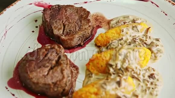 在盘子上旋转两个带有红酱和土豆装饰的烤肉片视频的预览图