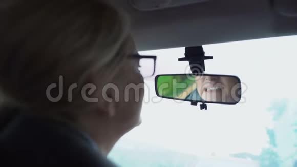 女人在汽车牙龈和牙齿敏感的后视镜里看着她的牙齿视频的预览图