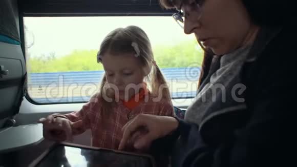 妈妈和女儿在火车上用平板电脑视频的预览图
