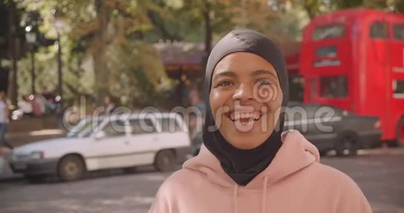 年轻漂亮的非裔美国穆斯林大学女孩戴着头巾微笑着幸福地站着视频的预览图