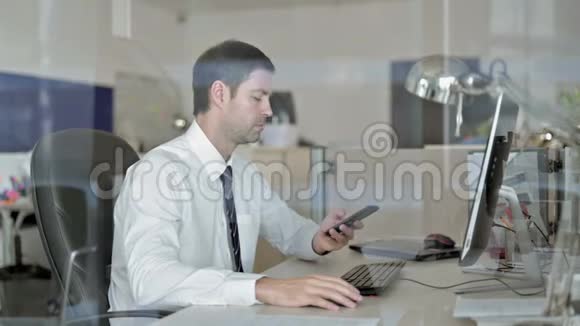 野心勃勃的中年商人在办公室里用手机说话视频的预览图