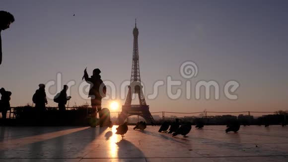 埃菲尔铁塔背景上的人和鸽子的剪影一个人走过摄像机慢动作视频的预览图