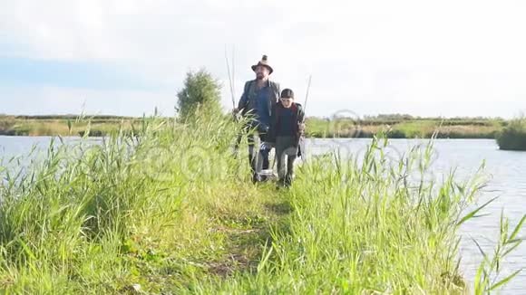 快乐的儿子去钓鱼的地方父亲跟着他们拿着鱼竿视频的预览图