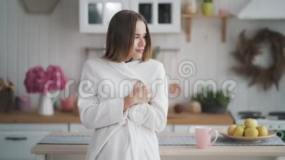 穿着白色浴袍的女人在家受凉冻僵了视频的预览图
