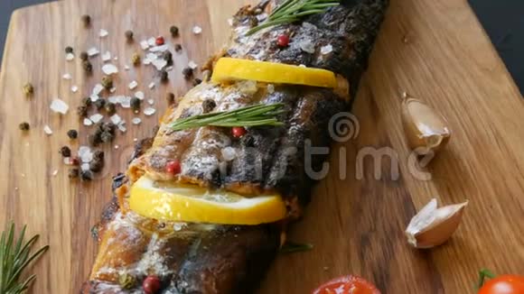 美味的新鲜鱼烟熏鲭鱼放在樱桃番茄旁边的木砧板上大蒜粗盐和视频的预览图