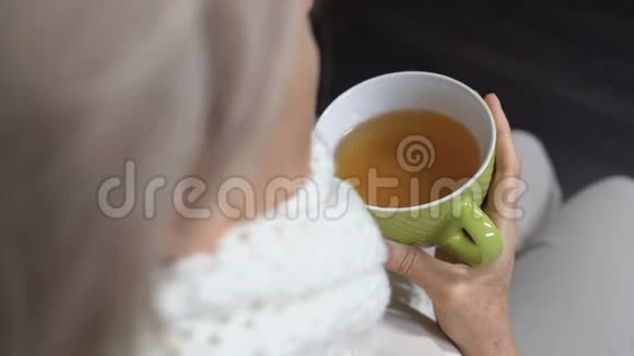 戴围巾的老年妇女咳嗽喝热茶季节性感冒治疗视频的预览图