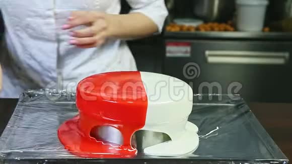 在金属台上的圆形芝士蛋糕上糖果师将红白镜釉平视频的预览图