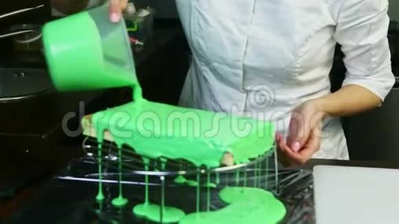 厨师统一配置的糖果在金属架上分层蛋糕上浇绿色釉视频的预览图