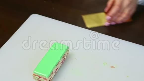 糖果师拿出一部分绿色釉面分层蛋糕放在金色的小摊上视频的预览图
