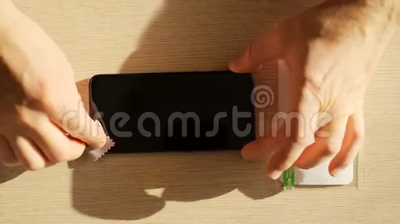 男性手清洁智能手机屏幕然后贴上保护膜视频的预览图