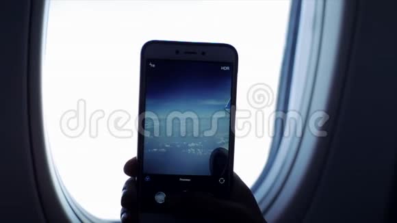 近距离观察一个人在飞机窗外用天空和云层的手机拍照视频的预览图