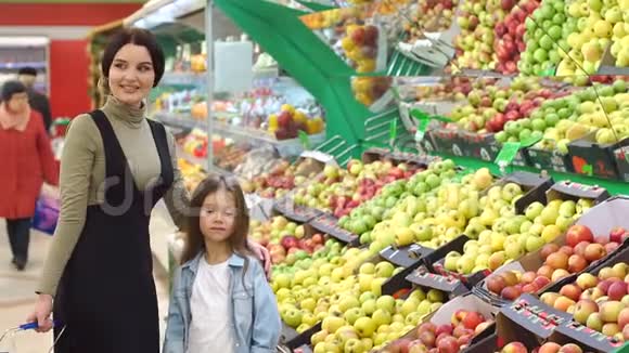 年轻的母亲和女儿在超市里选择苹果视频的预览图