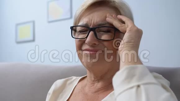 戴眼镜的老年妇女因高血压而头痛吃药视频的预览图