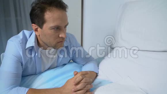 沮丧的男人看着空荡荡的病床试图应付他的悲伤失落视频的预览图