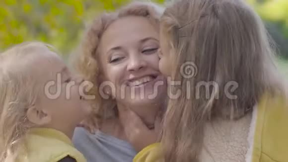 两个漂亮的白种人女孩亲吻母亲脸颊的肖像快乐的姐妹们向他们表达他们的爱视频的预览图