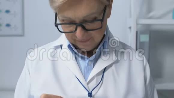友好的女医生穿着米色对着镜头微笑预约视频的预览图