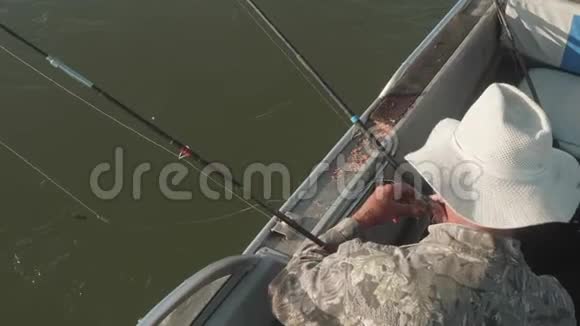戴着白帽子的白人渔夫把鱼饵放在鱼钩上把鱼钉扔进河里上景视频的预览图