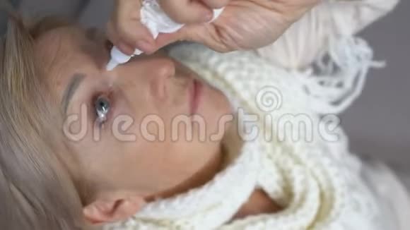 戴围巾的老妇人用眼药水从干燥健康支持药房视频的预览图