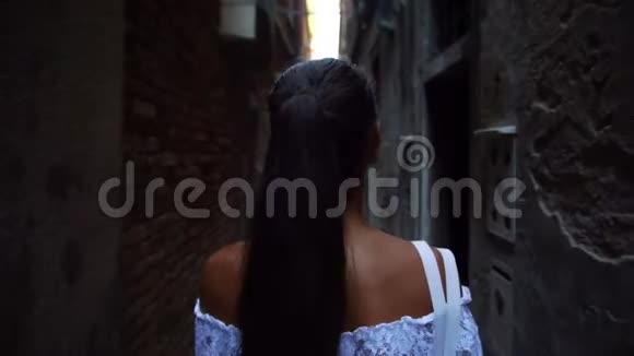 女孩走在狭窄的街道上看着威尼斯的老房子视频的预览图