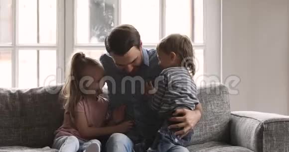 嬉戏的爸爸和可爱的弟弟妹妹一起在沙发上玩耍视频的预览图