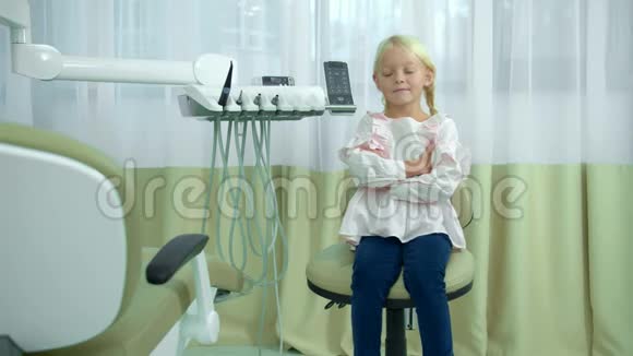 小女孩手牵手坐在牙科椅上视频的预览图