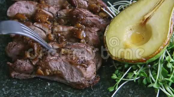 宏观人类双手用叉子和刀在黑色盘子上切下一片烤肉视频的预览图