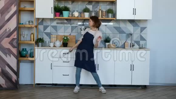 漂亮的年轻女人在厨房跳舞听音乐视频的预览图
