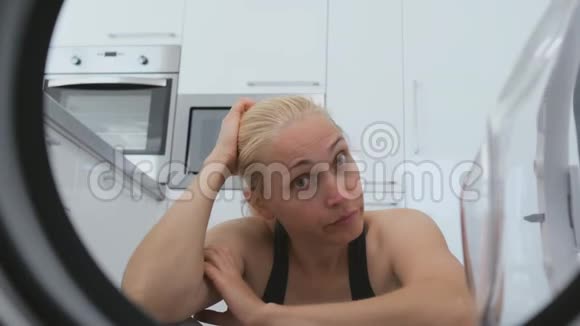 一个女人坐在洗衣机前看着里面的鼓视频的预览图