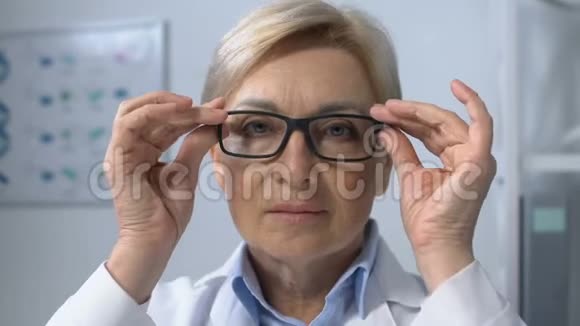 女士治疗师调整眼镜和看相机经验丰富的工人视频的预览图