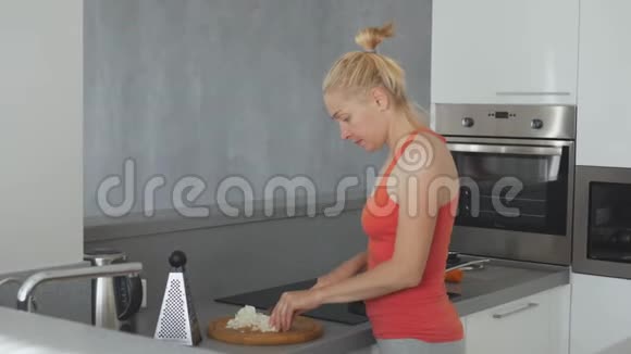 厨房里的一个女人正在准备晚餐在砧板上切洋葱视频的预览图