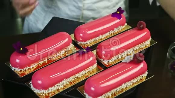 糖果展示了五个粉红色的带有覆盆子和花花装饰的光滑椭圆形蛋糕视频的预览图
