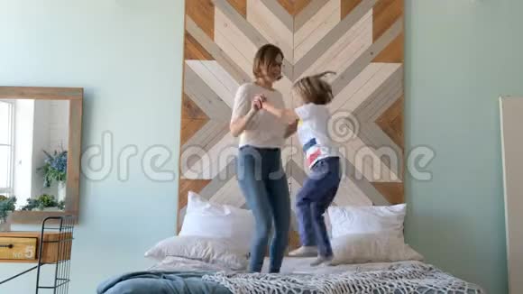兴奋的孩子躺在床上活泼的年轻妈妈和她的儿子一起跳早晨视频的预览图