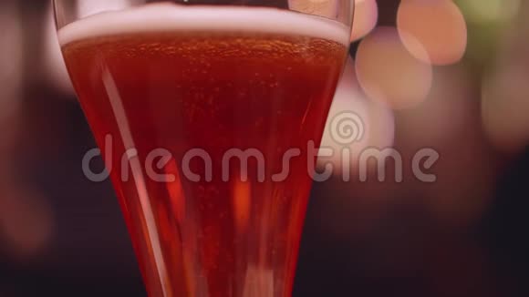 在一杯啤酒里小泡泡不断地冒出来背景灯的非焦点视图慢镜头视频的预览图