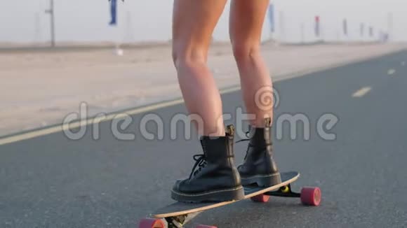 女孩骑着滑板在沙丘之间的沙漠道路上快关门视频的预览图