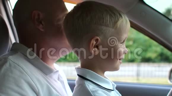 一个小男孩和他的父亲坐在汽车的车轮后面学习开车视频的预览图
