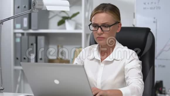 女商人紧张地摘下眼镜关闭手提电脑工作问题视频的预览图