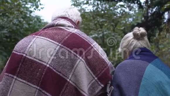 穿格子花格衣的老人和妻子在公园边用手杖走路照顾家视频的预览图