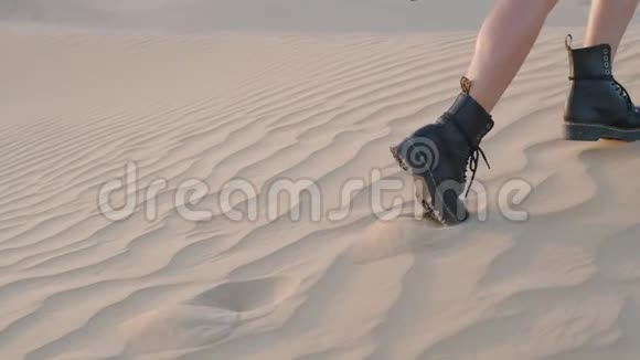 一个带着滑板的女孩沿着沙漠中的沙丘散步慢动作视频的预览图
