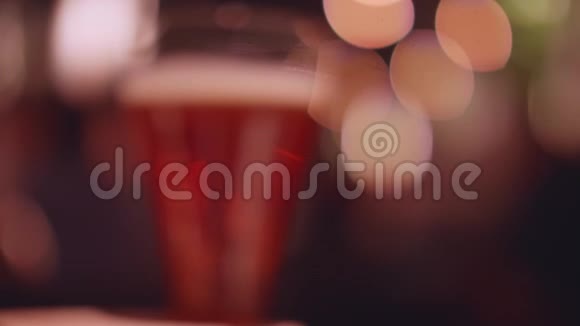 对啤酒杯的离焦视图接近摄像机并变得聚焦慢动作视频的预览图