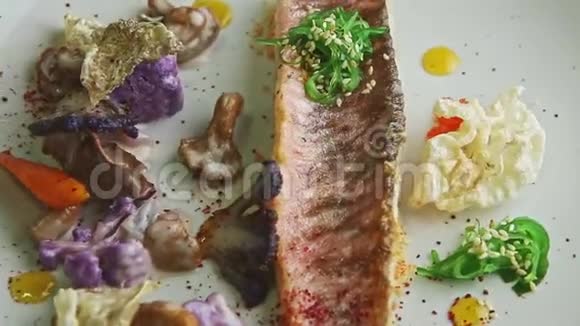 上景特写精细装饰的烤鱼片与蔬菜旋转在盘子上视频的预览图