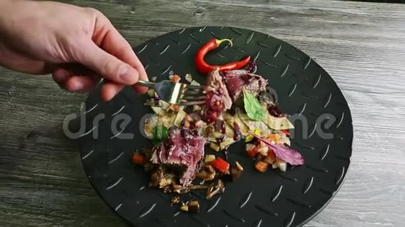 人的手从烤肉中取出小块从黑色盘子中取出叉子视频的预览图