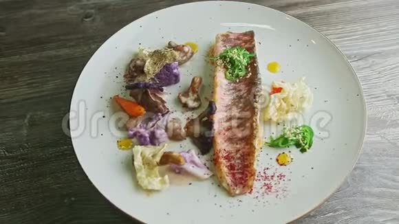 精致的烤鱼片和切好的蔬菜在盘子上旋转视频的预览图