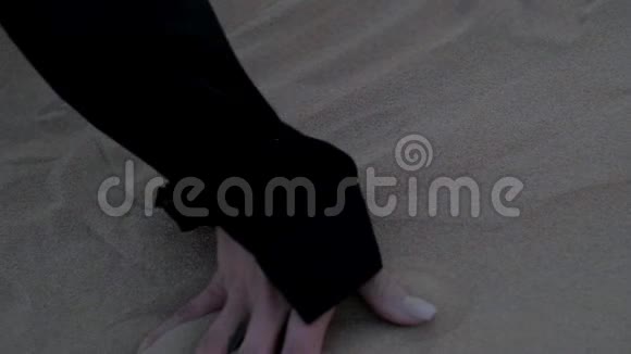 一个女孩躺在沙漠中的沙丘上的手慢动作特写视频的预览图