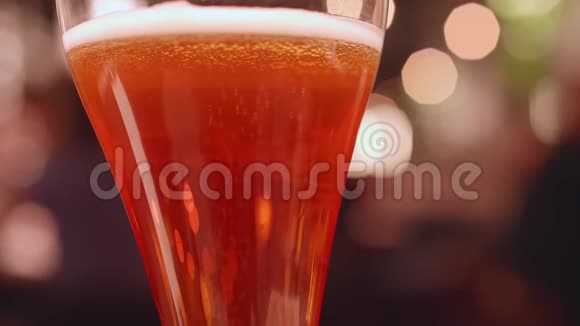 在一杯啤酒里小泡泡不断地冒出来背景灯的非焦点视图视频的预览图