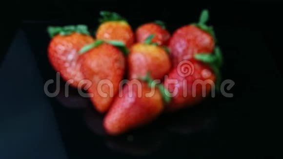 把注意力集中在黑色背景下的一组新鲜多汁的红色草莓上视频的预览图