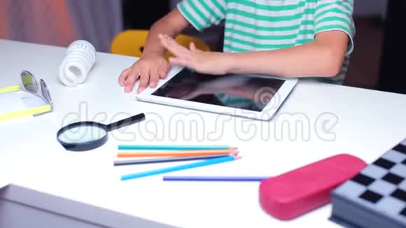 特写镜头一个坐在桌旁的少年擦着平板电脑屏幕视频的预览图